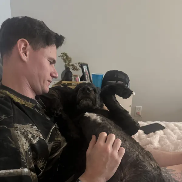 Bryan giving a black dog belly rubs on the couch