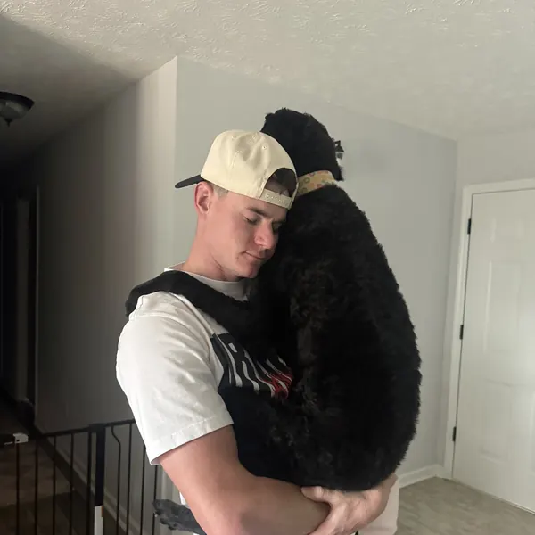 Bryan hugging a big black doodle